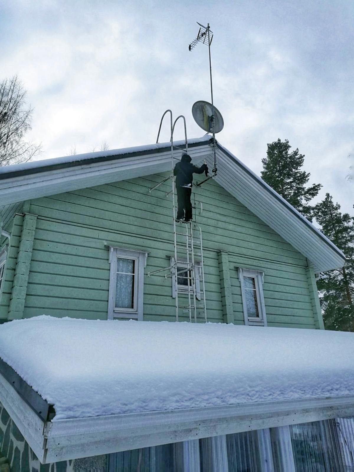 Man som klättrar uppför stege på hus