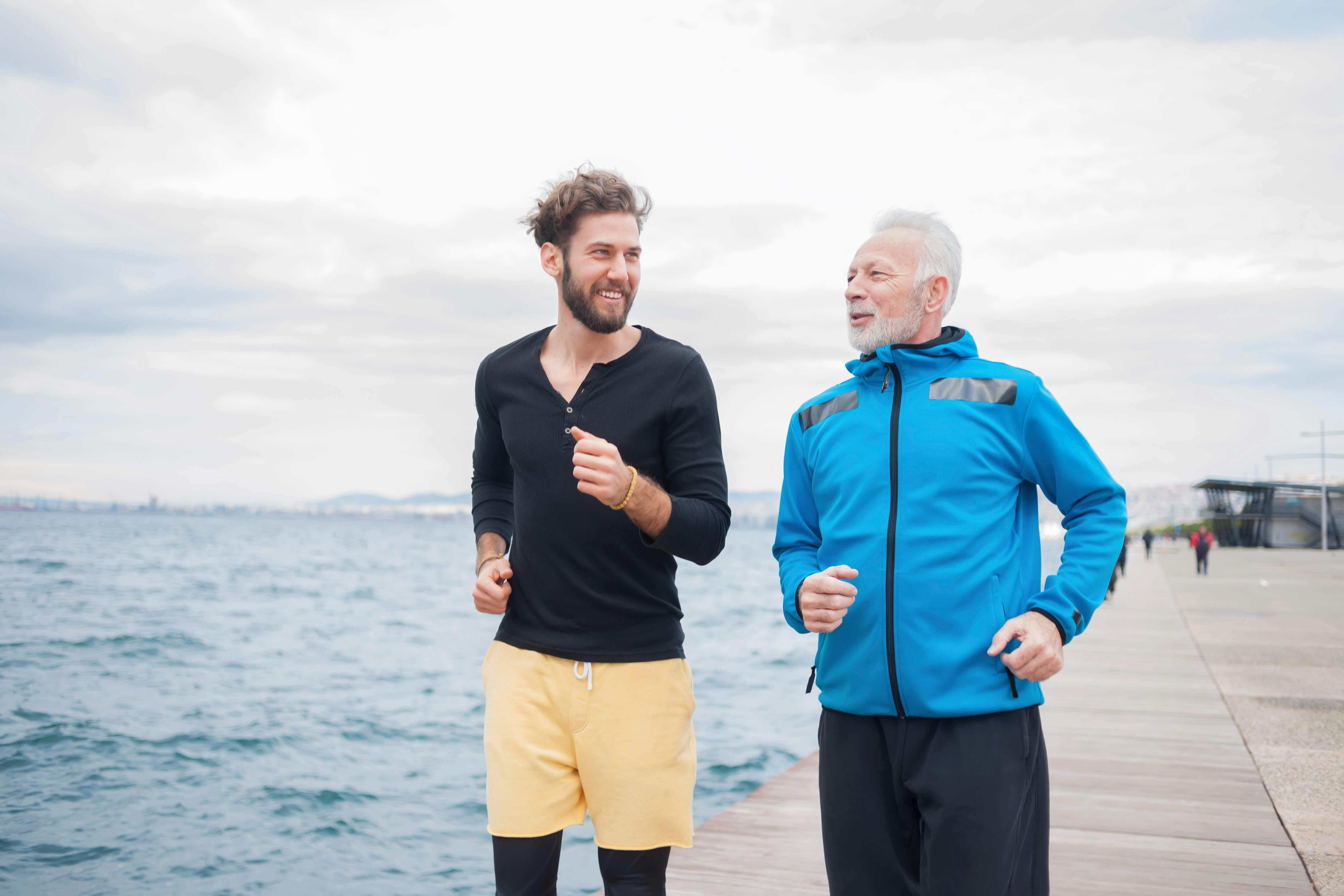 Løb flere sammen - det styrker motivationen. yngre mand og ældre mand løber sammen langs havet