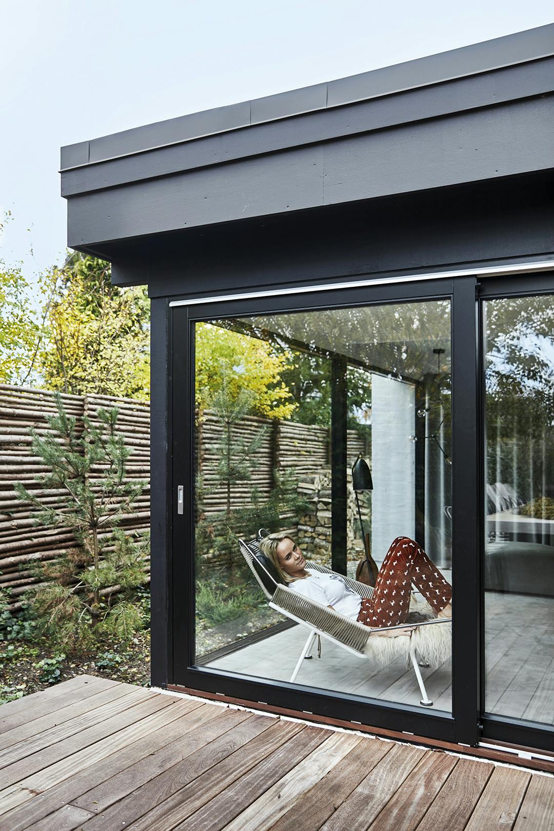 MAJBRITT JOHANSEN, eigenaar van designunit.dk, mag graag relaxen in de Flag Halyard Chair van Hans J. Wegner. Glazen pui aan terras, met designer stoel.