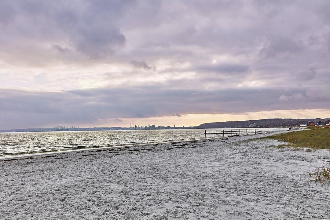 Het huis staat dicht bij het strand, waar het gezin vaak naartoe gaat. Strand in de avond met paarse lucht.