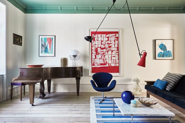 Qua kleuren liet Michael zich inspireren door de primaire kleuren van het Bauhaus, blauw, groen en rood, maar dan in wat meer gedekte en rustige varianten. kleurrijke scandinavische woonkamer inrichting met vleugel piano