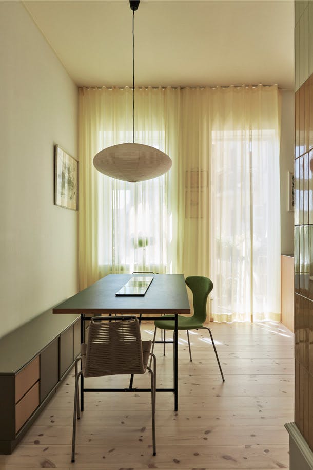 De eettafel is van Please Wait to be Seated, en daarboven hangt een hanglamp van Isamu Noguchi voor Vitra. Rond de tafel staan de PK1-stoel van Poul Kjærholm en een Mosquito Chair van Arne Jacobsen. De bank is een kastelement van Montana. Eettafel in eetkeuken met transparante gordijnen en houten vloer