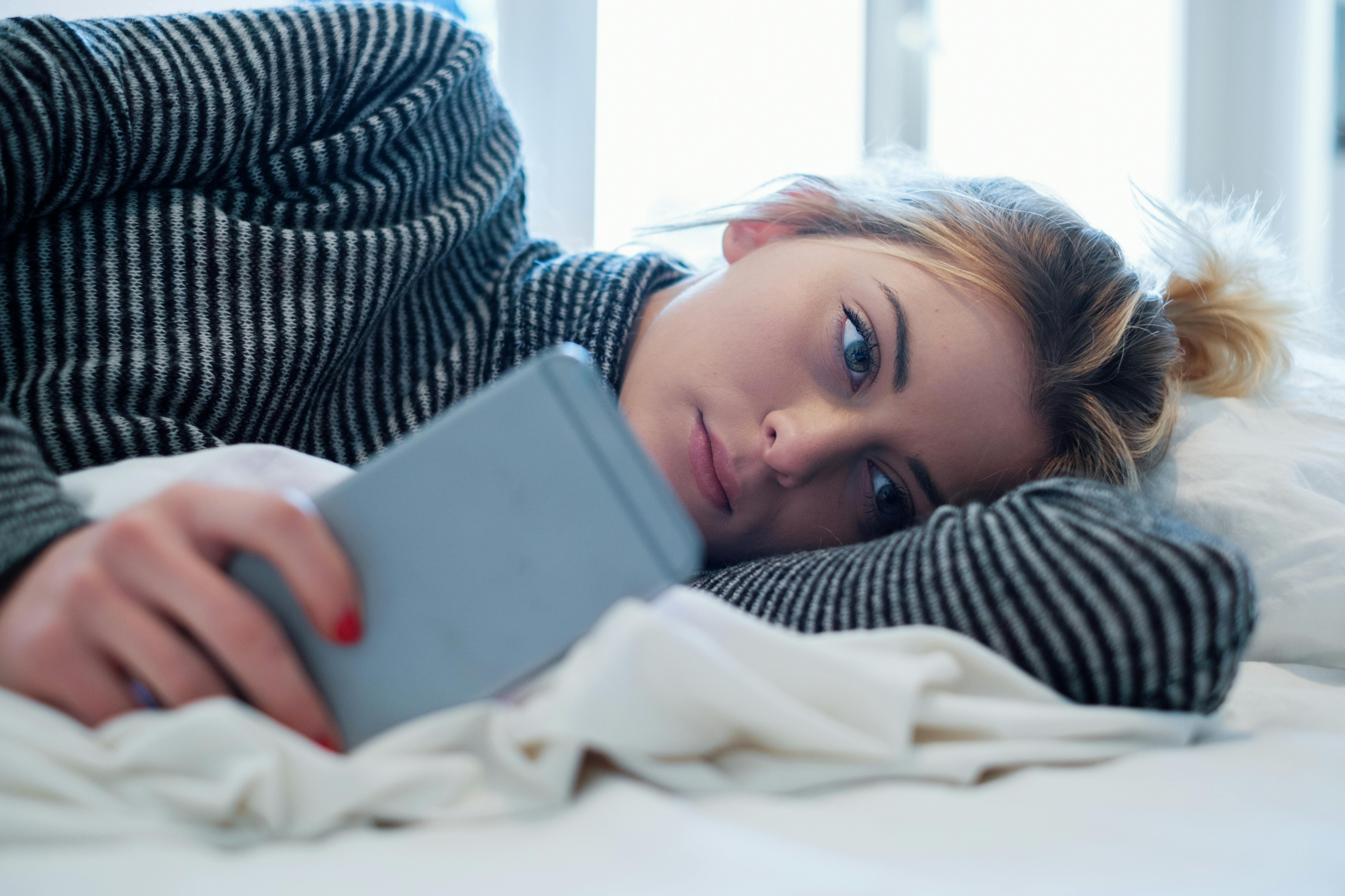 De sociale medier er det sted, vi sammenligner os mest med hinanden. Kvinde ligger og kigger på sin mobil