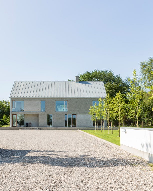 De simpele lijnen van de architectuur herinneren aan de oude boerderij, maar dan met de allure van een modern landhuis. moderne architectuur woonboerderij van grijze baksteen