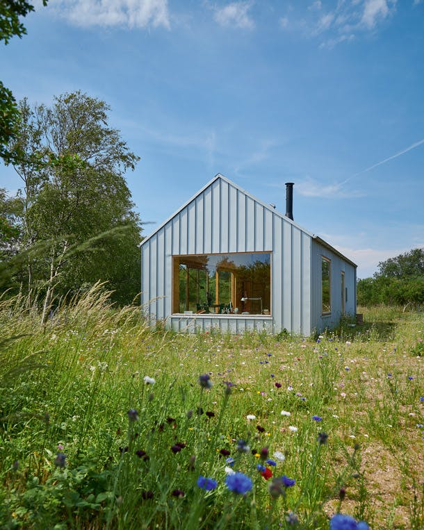 Het strakke huis is opgetrokken uit gelakte, lichtgrijze stalen profielen van DS Stålprofil. Stalen design vakantiewoning in de natuur