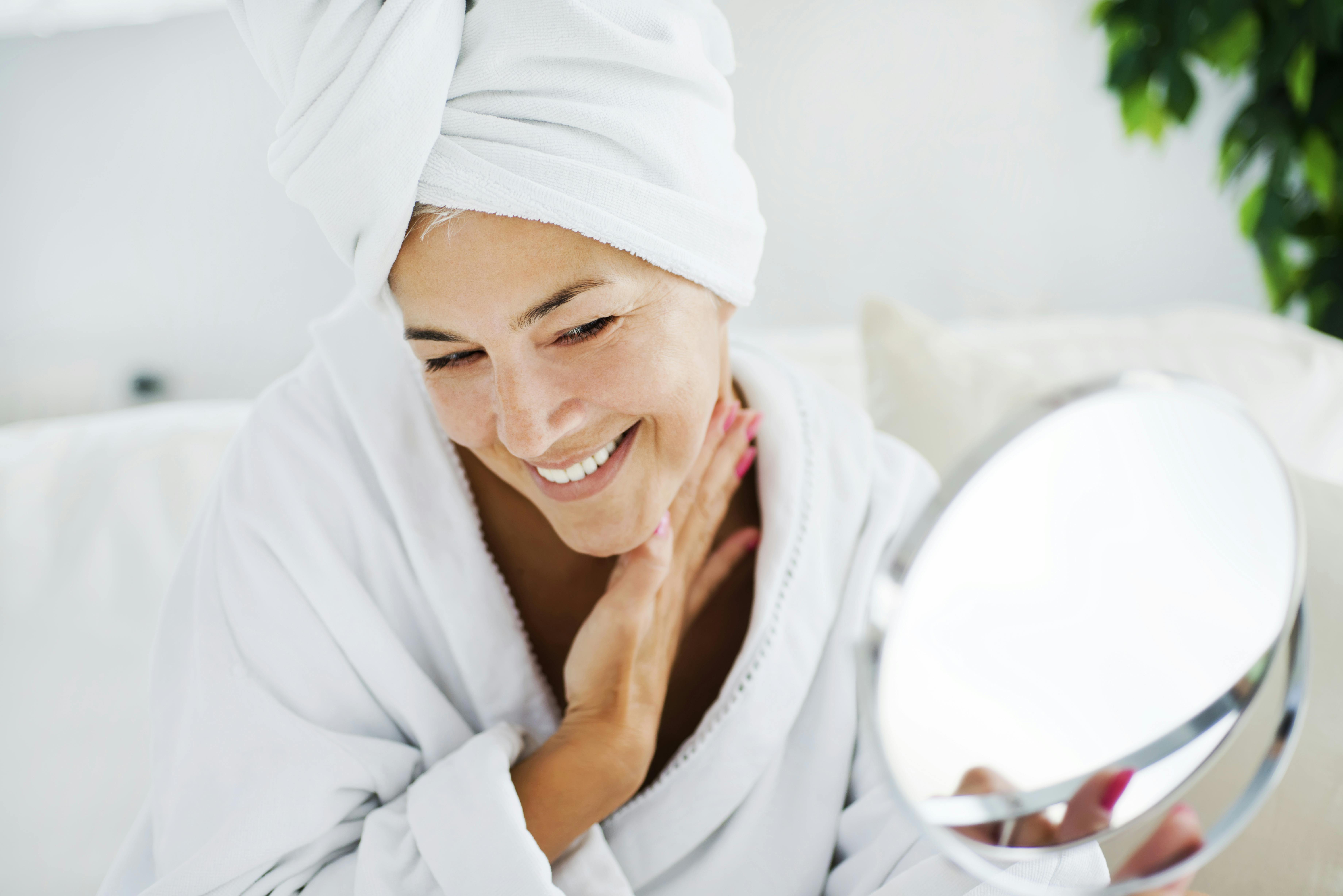 Din øjenmakeup er flot. Men den skal altså af, inden du renser dit ansigt! Moden kvinde renser ansigt og kigger sig i spejlet
