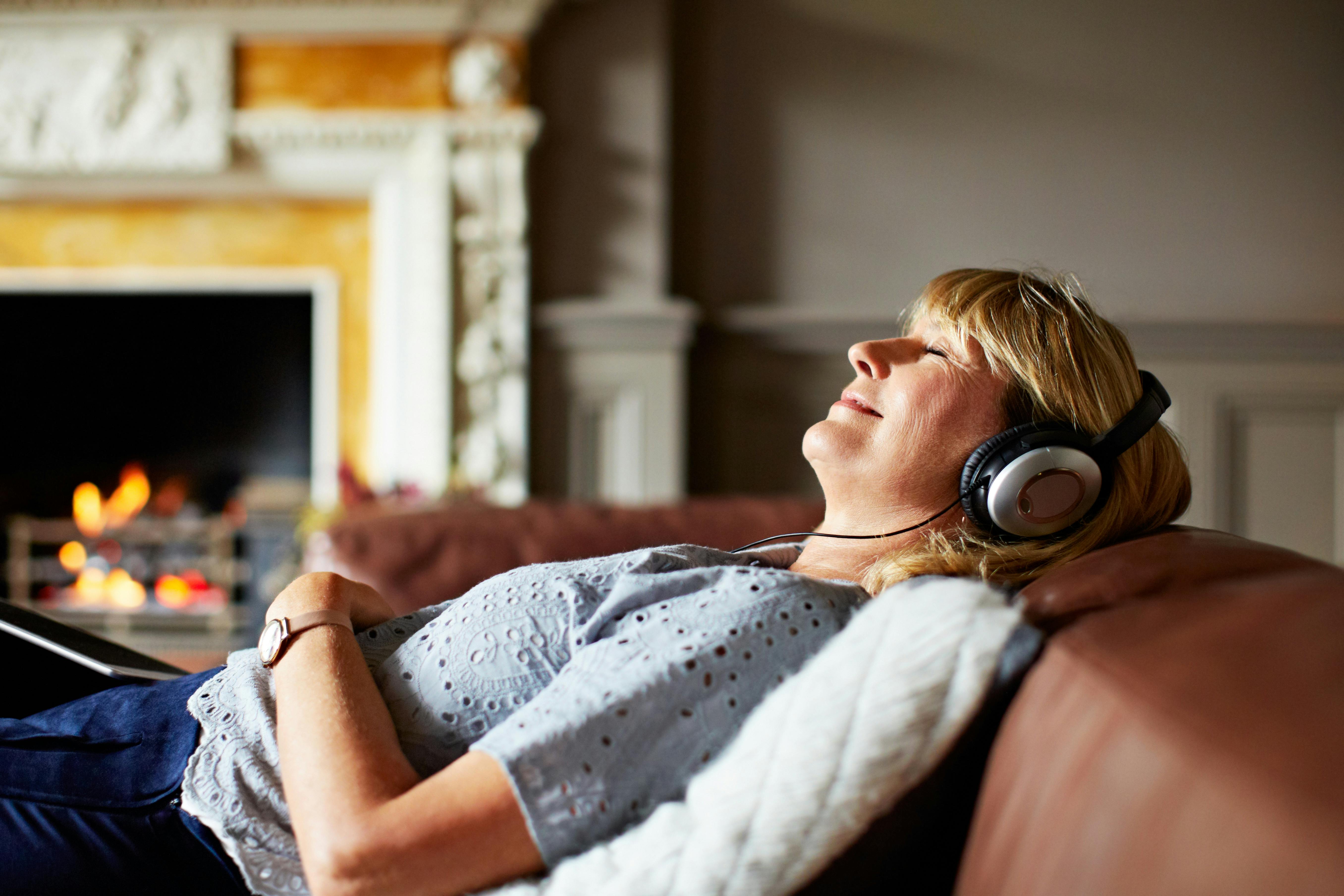 I stedet for at se frem mod den ultimative pause, pensionen, handler det om at holde mindre pauser undervejs. Moden kvinde slapper af i sofa og hører musik