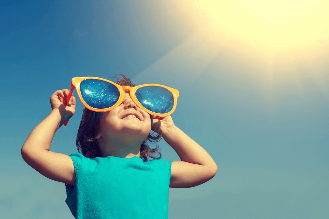 Juster din interne klokke med dagslys. liten smilende jente med solbriller ser på solen