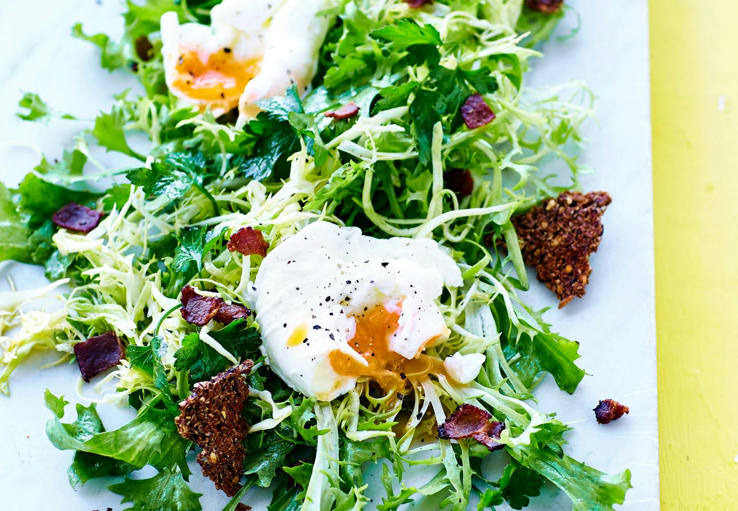 Pocherat ägg, sallad och rågbrödschips på marmorbricka