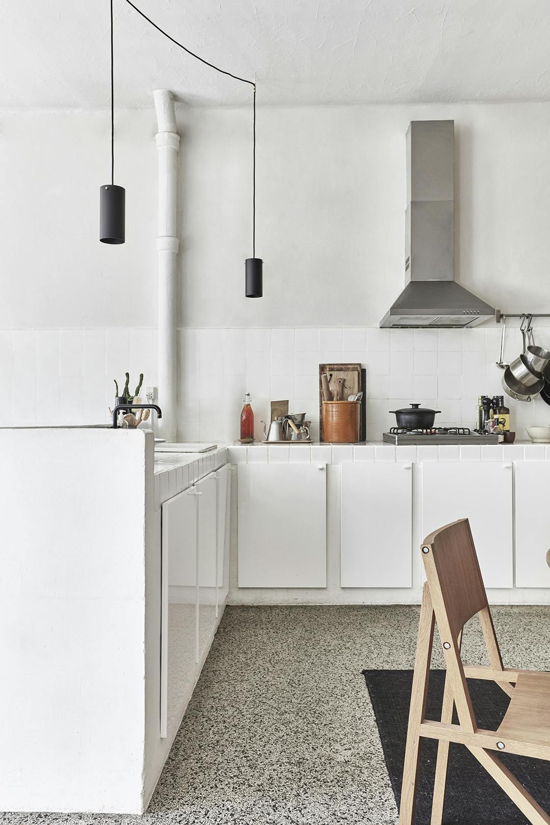 In de keuken zie je de originele witte tegels uit de tijd dat de woning nog een koekjesfabriek was. Industriële keuken met terrazzovloer, oude koekjesfabriek