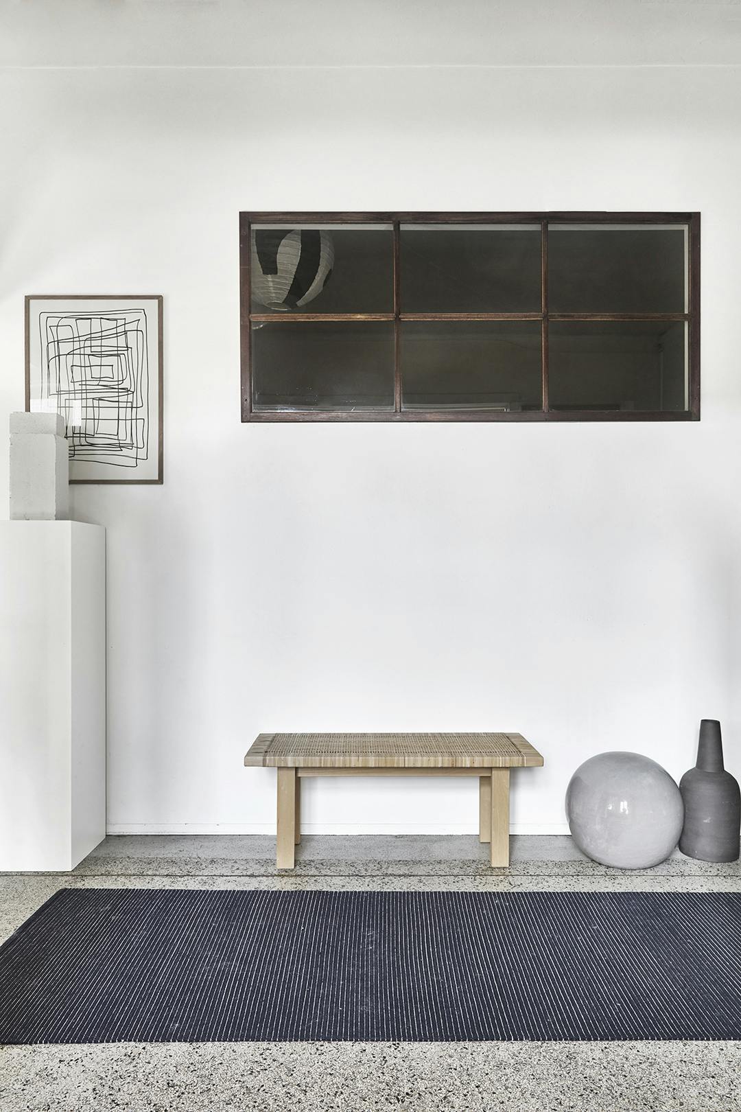 In de gang zie je Sara’s liefde voor Japanse interieurs terug in de simpele lijnen, het Ikea-bankje van rotan en essenhout en de weinige, maar goed gekozen keramieken objecten. Japans Ikea rotan bankje, lijntekening en keramiek