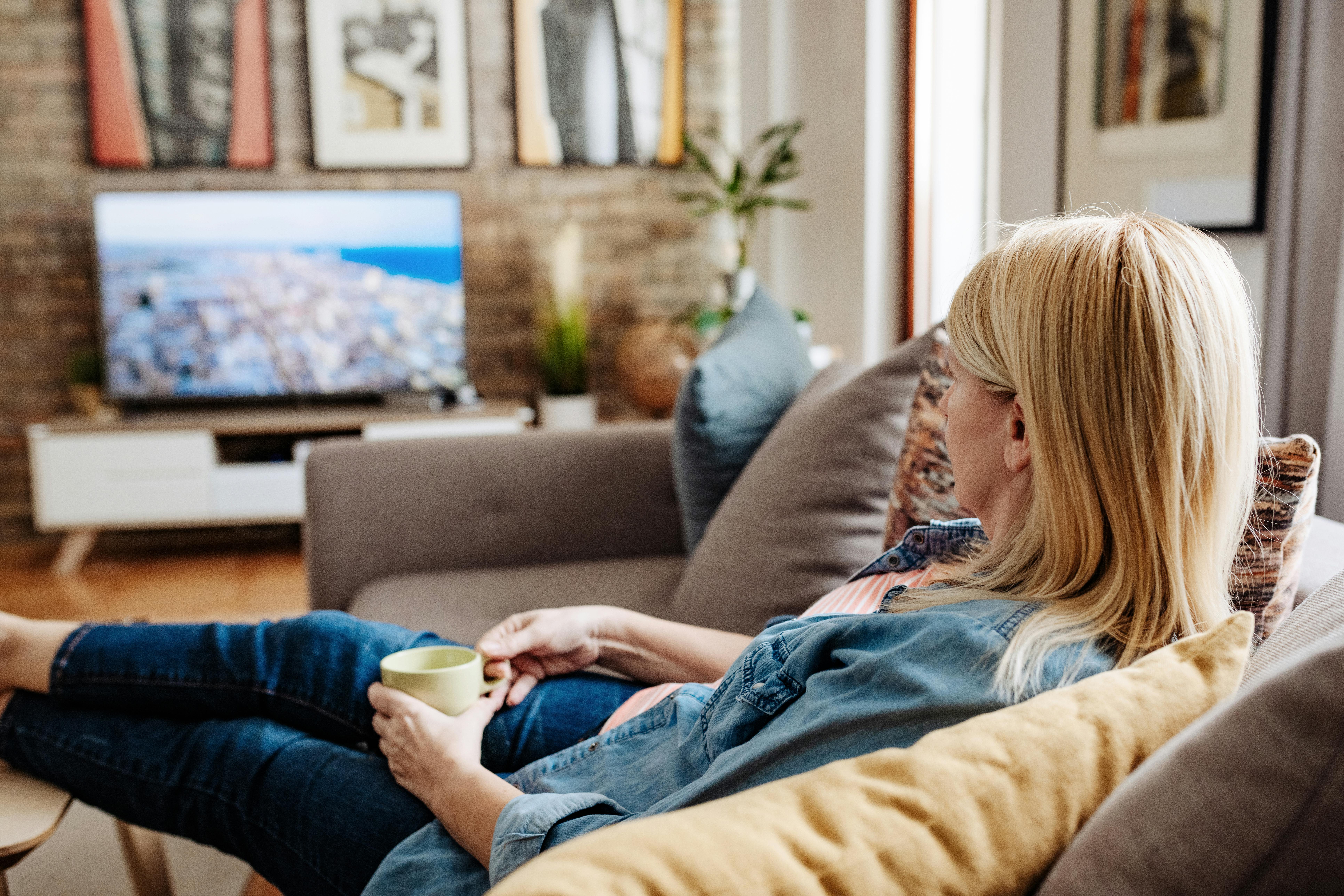 Når du tuner ind i en tv-serie, giver du din hjerne noget andet at tænke på, en pause fra dine bekymringer. Kvinde ser tv i sofaen