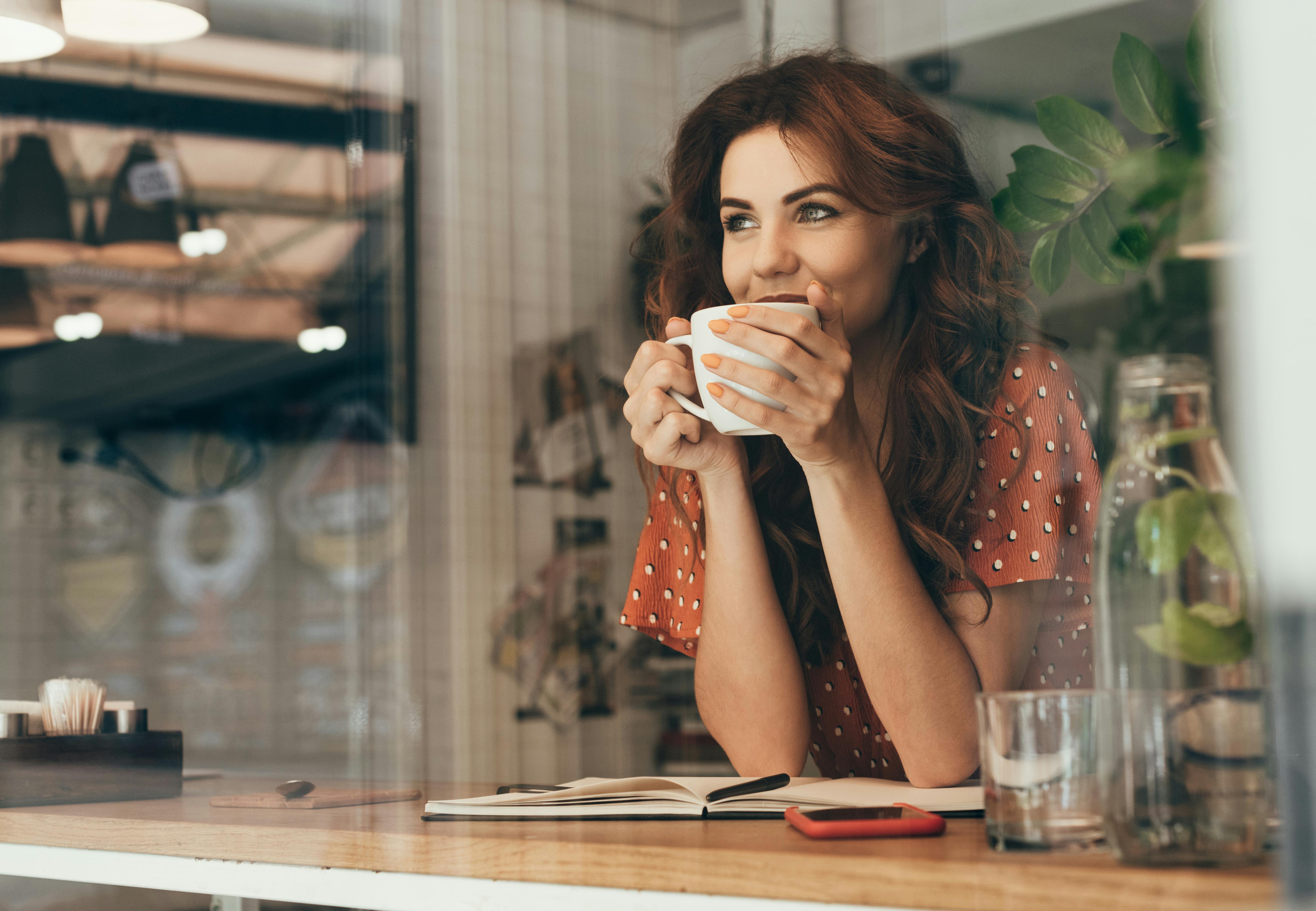 Kvinne drikker kaffe inne.