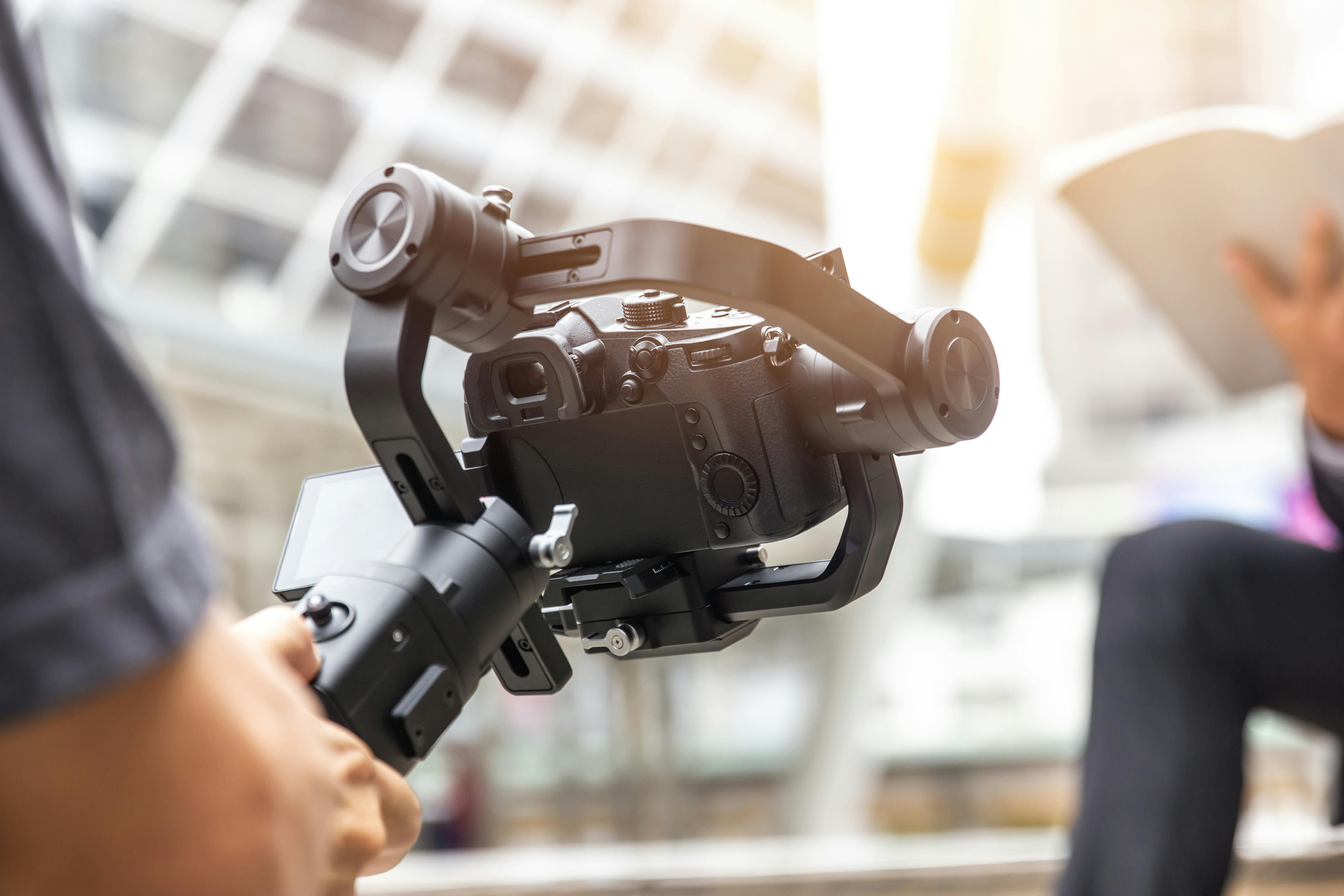 en mand filmer med en gimbal i modlys