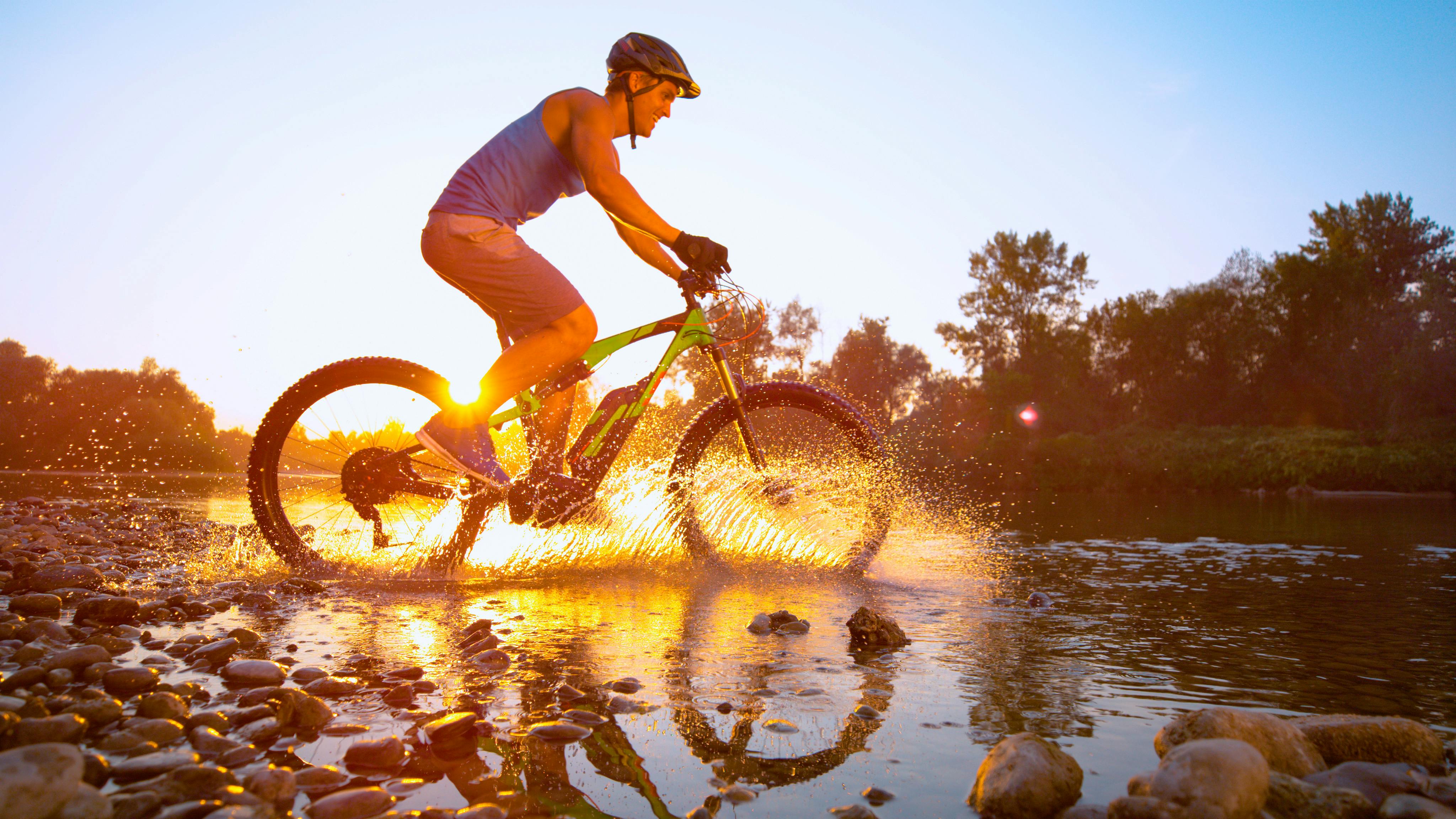 Billede af mountainbikerytter i sø i modlys