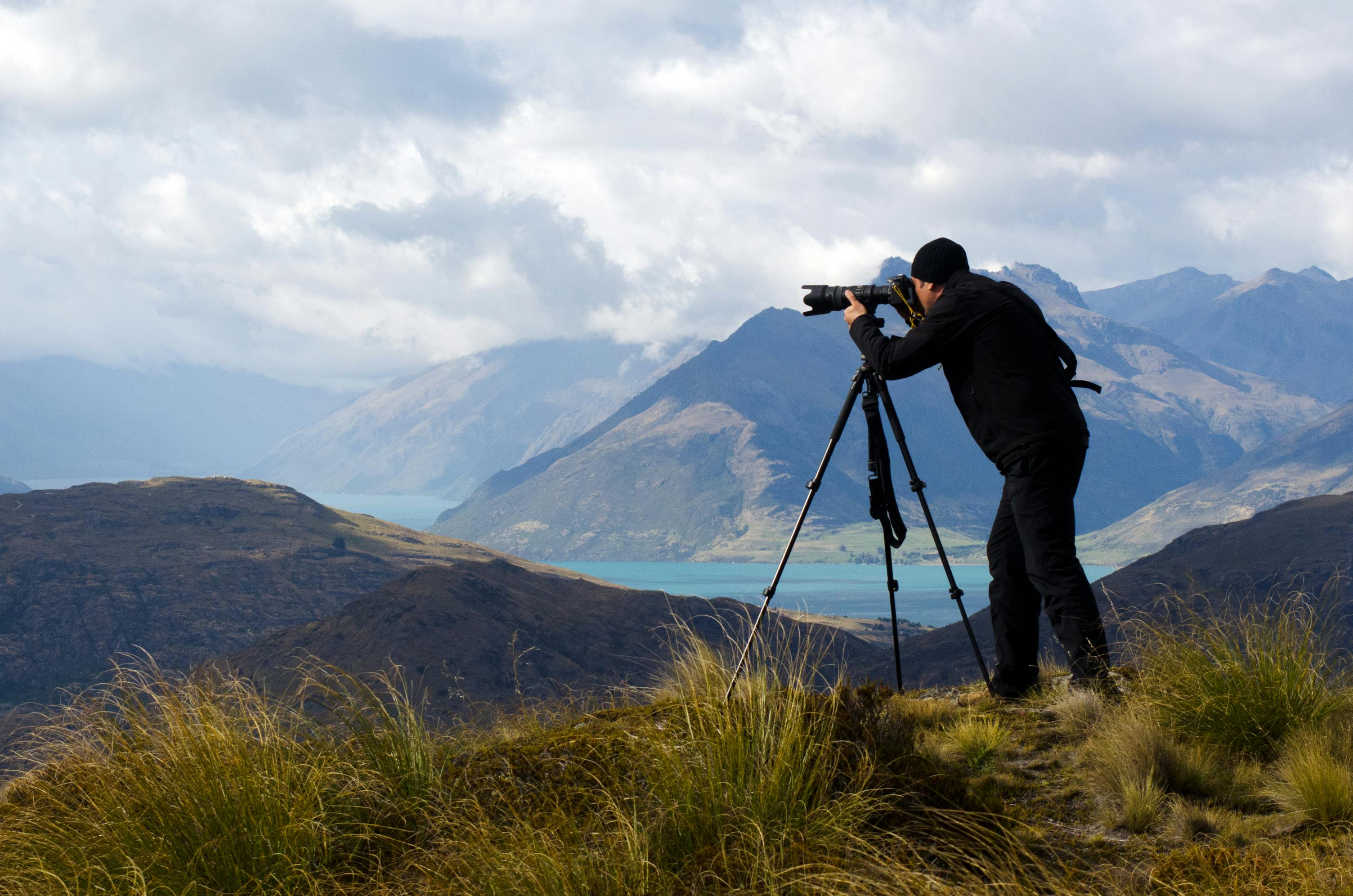 En mann fotograferer med kameraet på et stativ