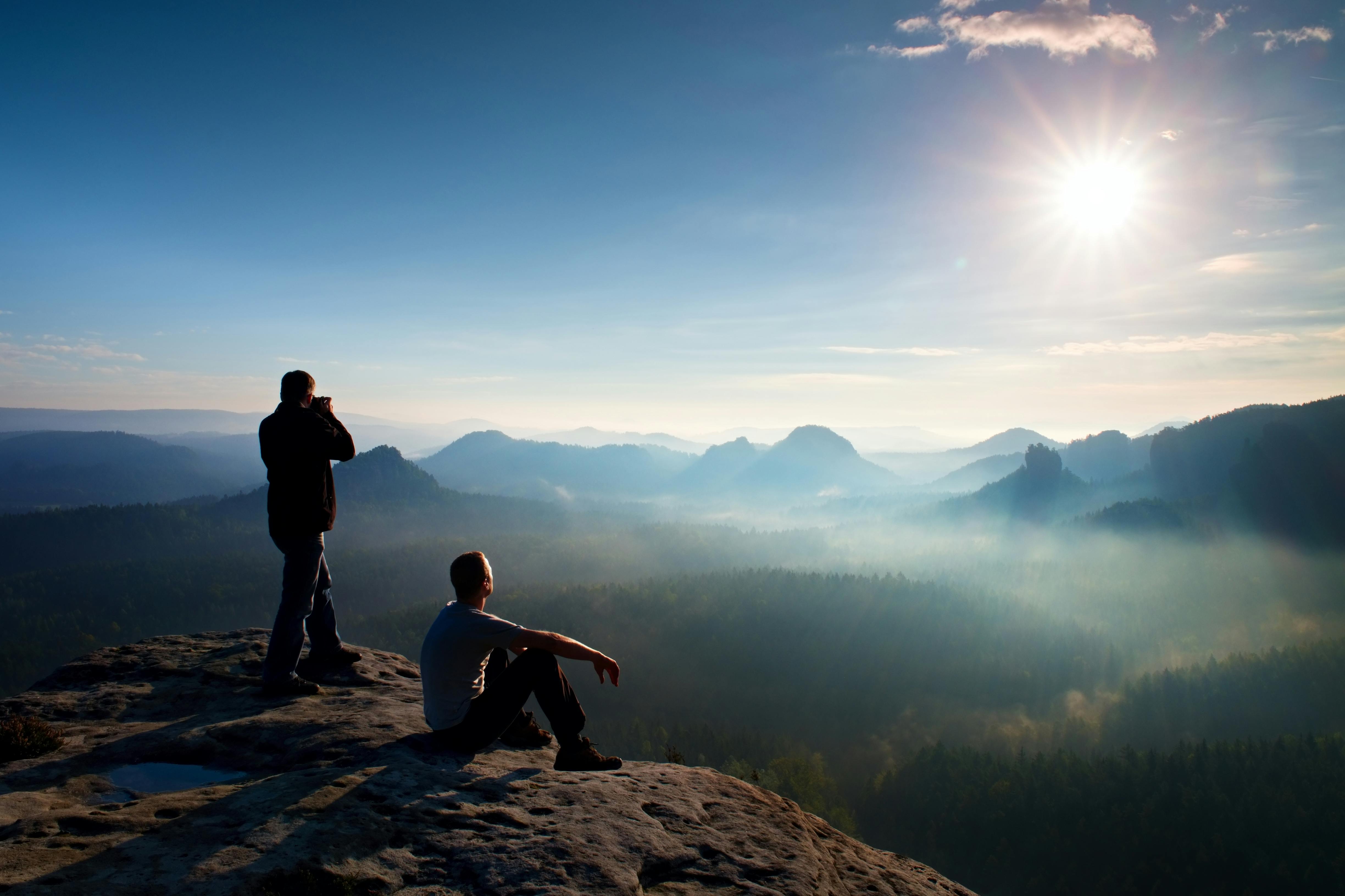 Mann på fjell fotograferer solnedgangen