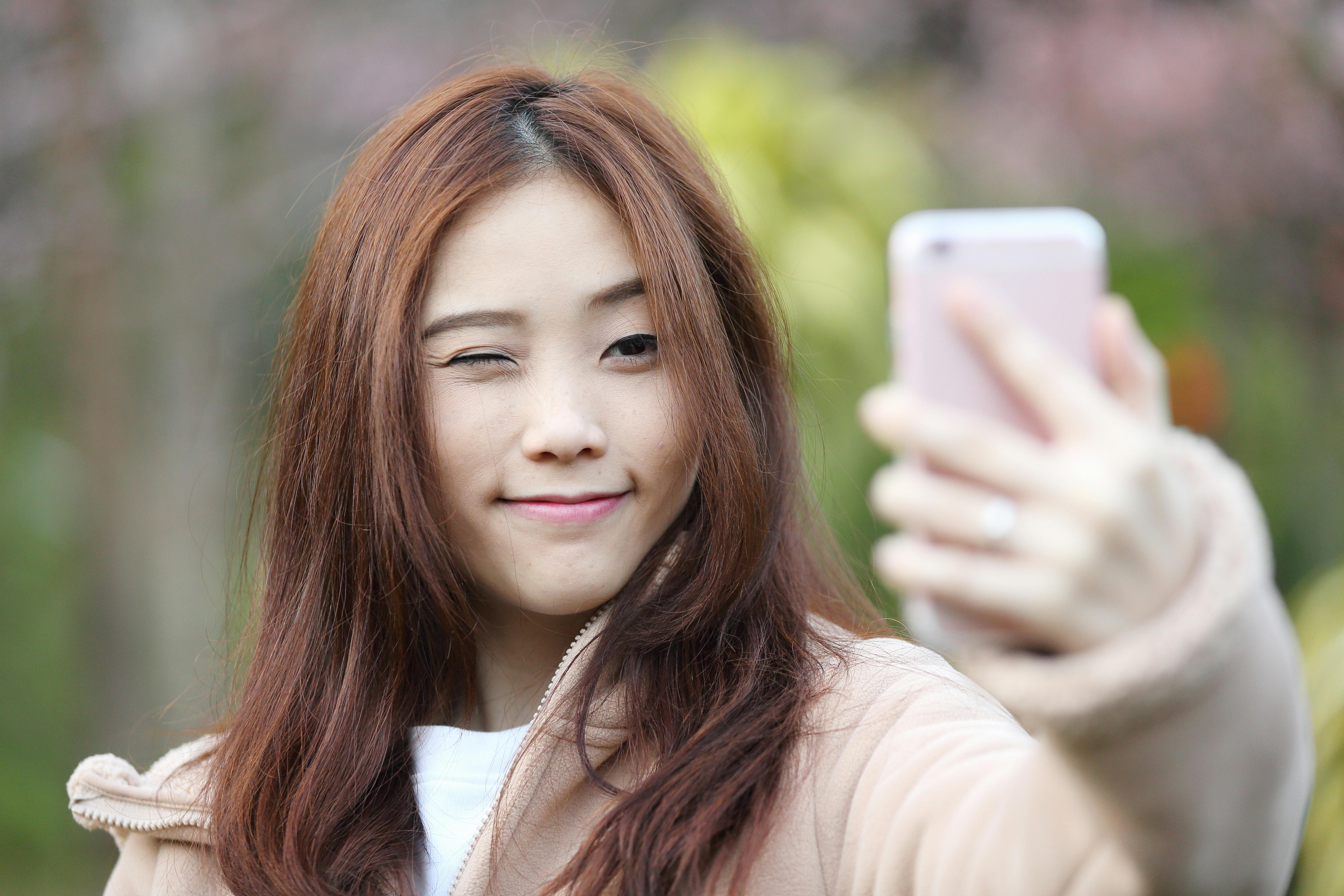 Ung tjej tar en selfie genom att använda volymknappen som avtryckare