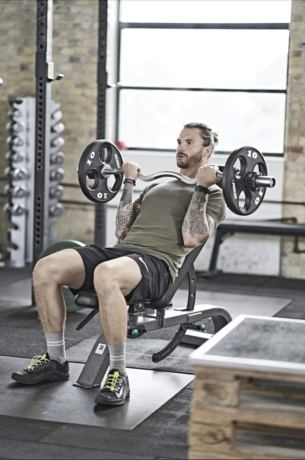 Mand, der udfører half curls med EZ-bar