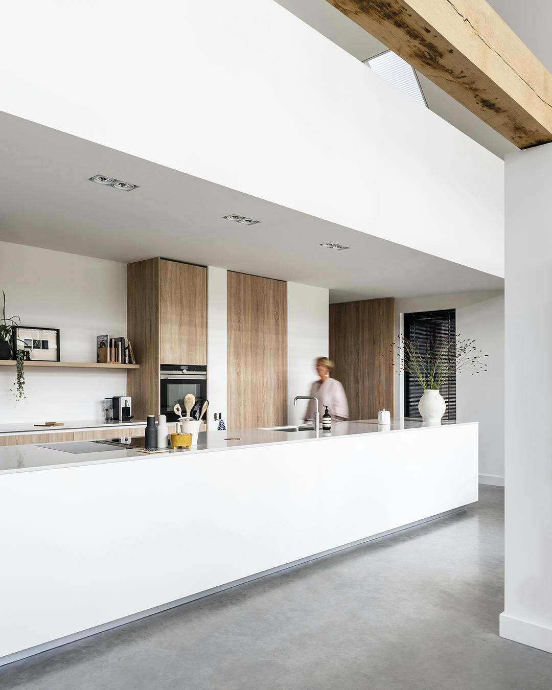 De keuken is in een soort alkoof geplaatst, maar oogt toch licht dankzij het gebruik van wit en hout. De keukenelementen zijn van Comprex. Comprex keuken met wit kookeiland en houten kasten
