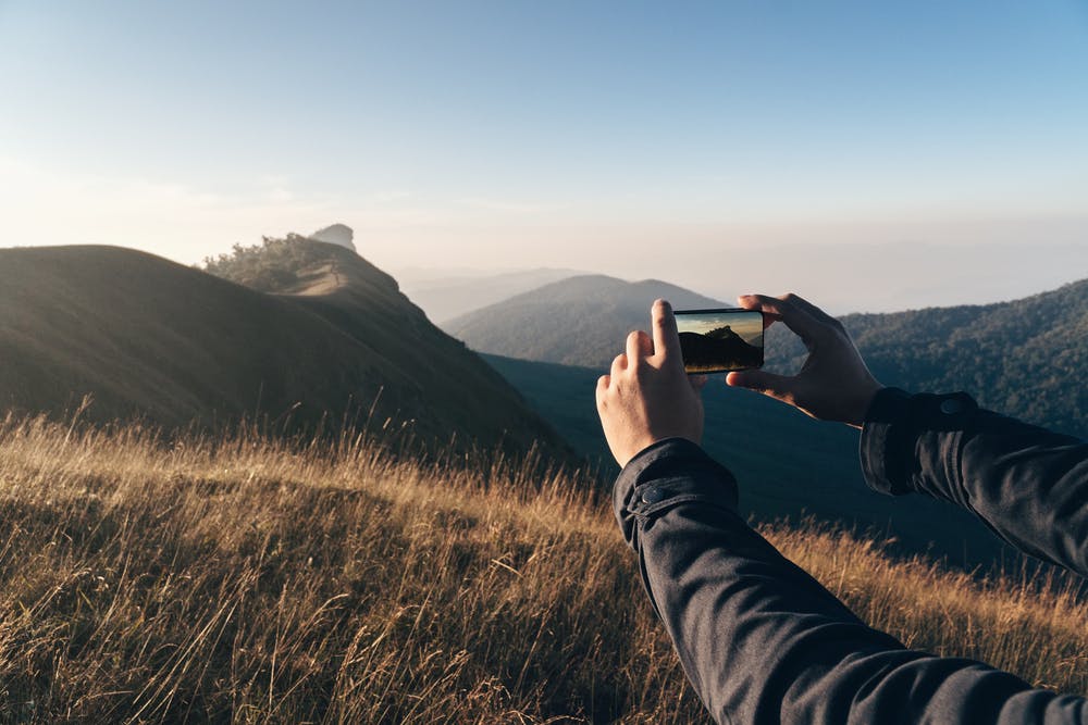 Mobilfotografering på en bakketopp i gyllent lys