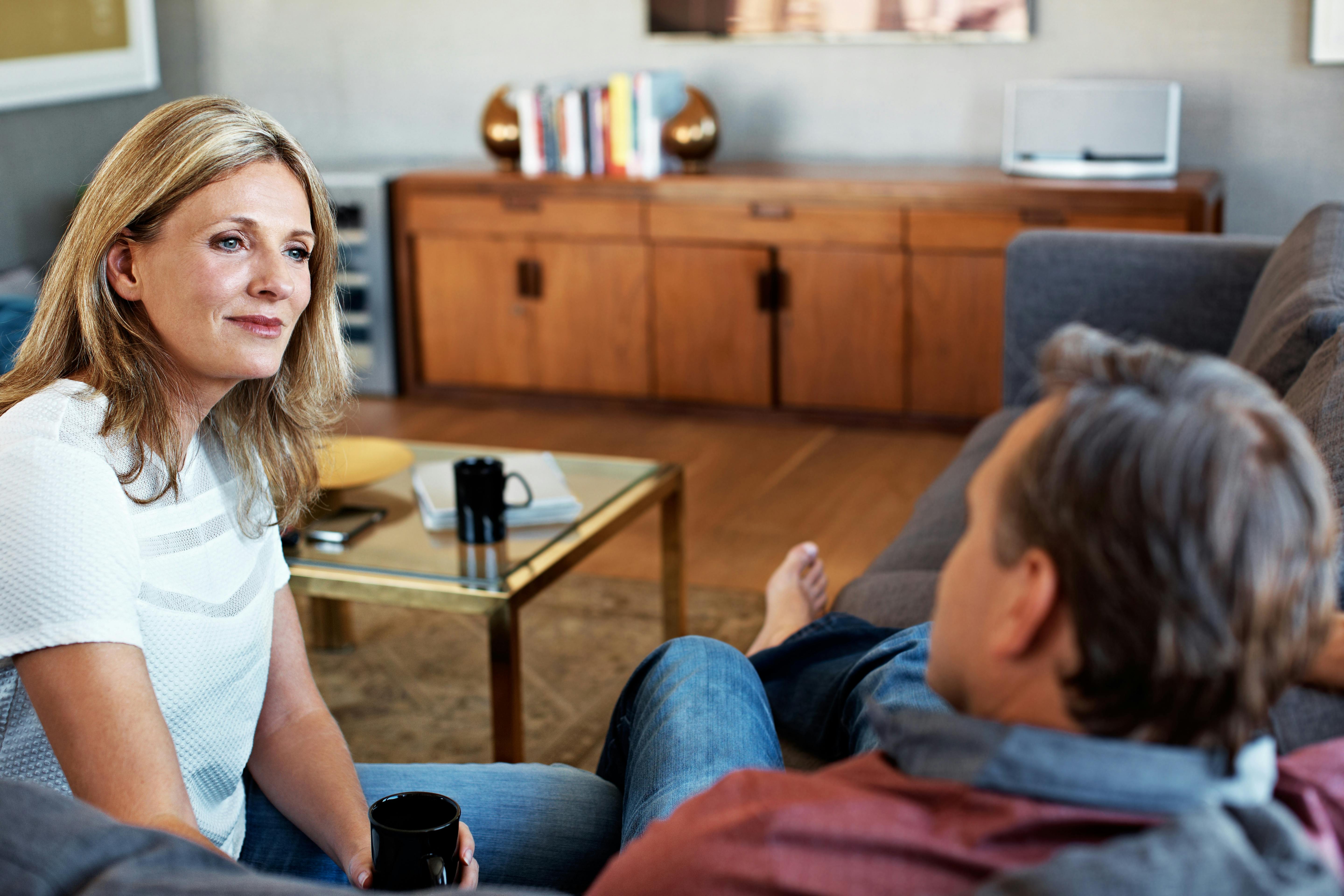 Det er en god idé at snakke med din partner om, hvad du har brug for for at føle dig tilfredsstillet. Modent par sidder i stuen og snakker med hinanden