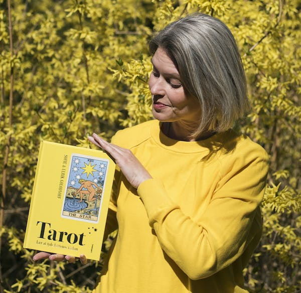 Tarotcoach Sofie Golodnoff med sin bog om tarotkort. Sofie Golodnoff i gult med gul bog om tarot.