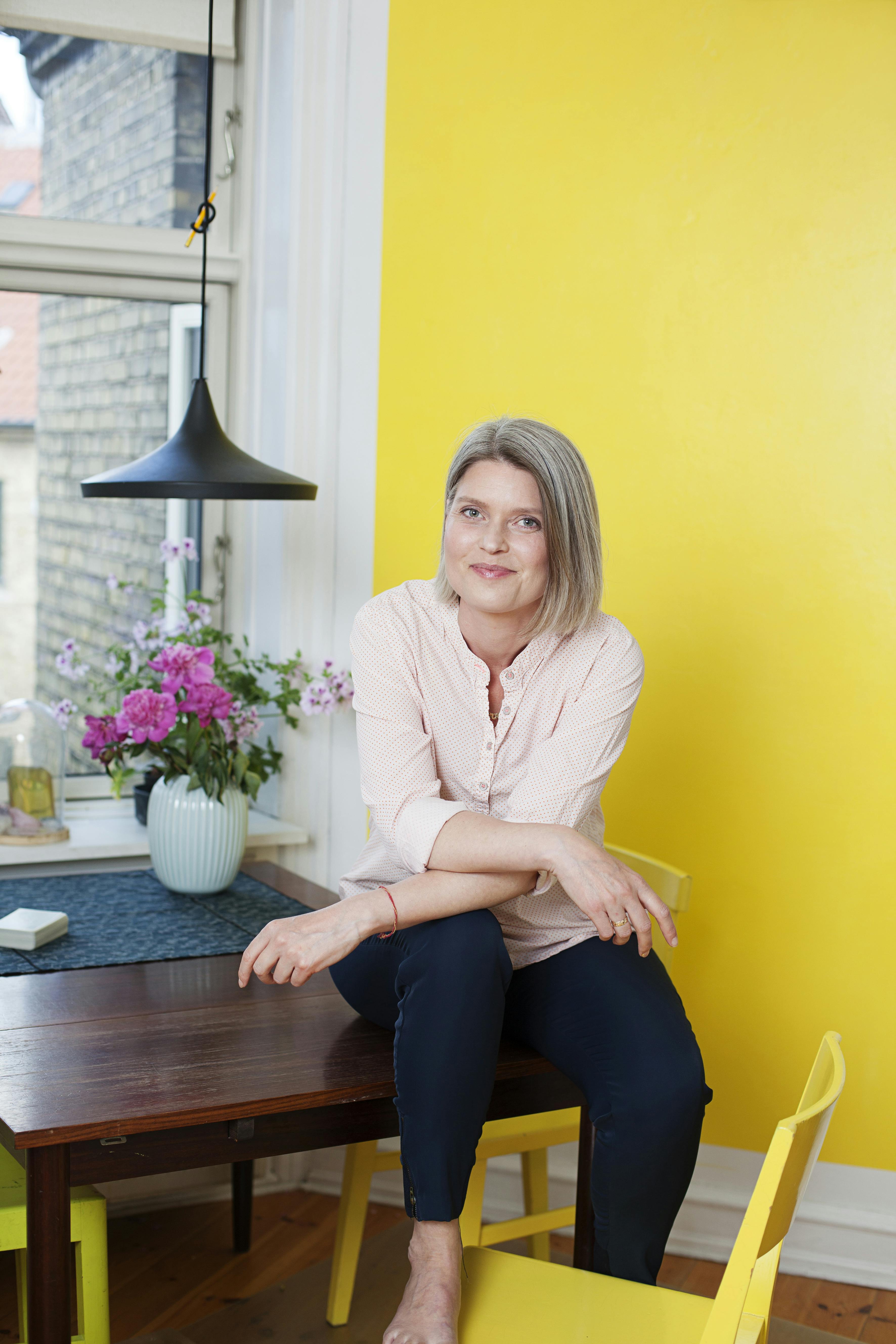 Tarotcoach Sofie Golodnoff med sin bog om tarotkort. Sofie Golodnoff i gult med gul bog om tarot.