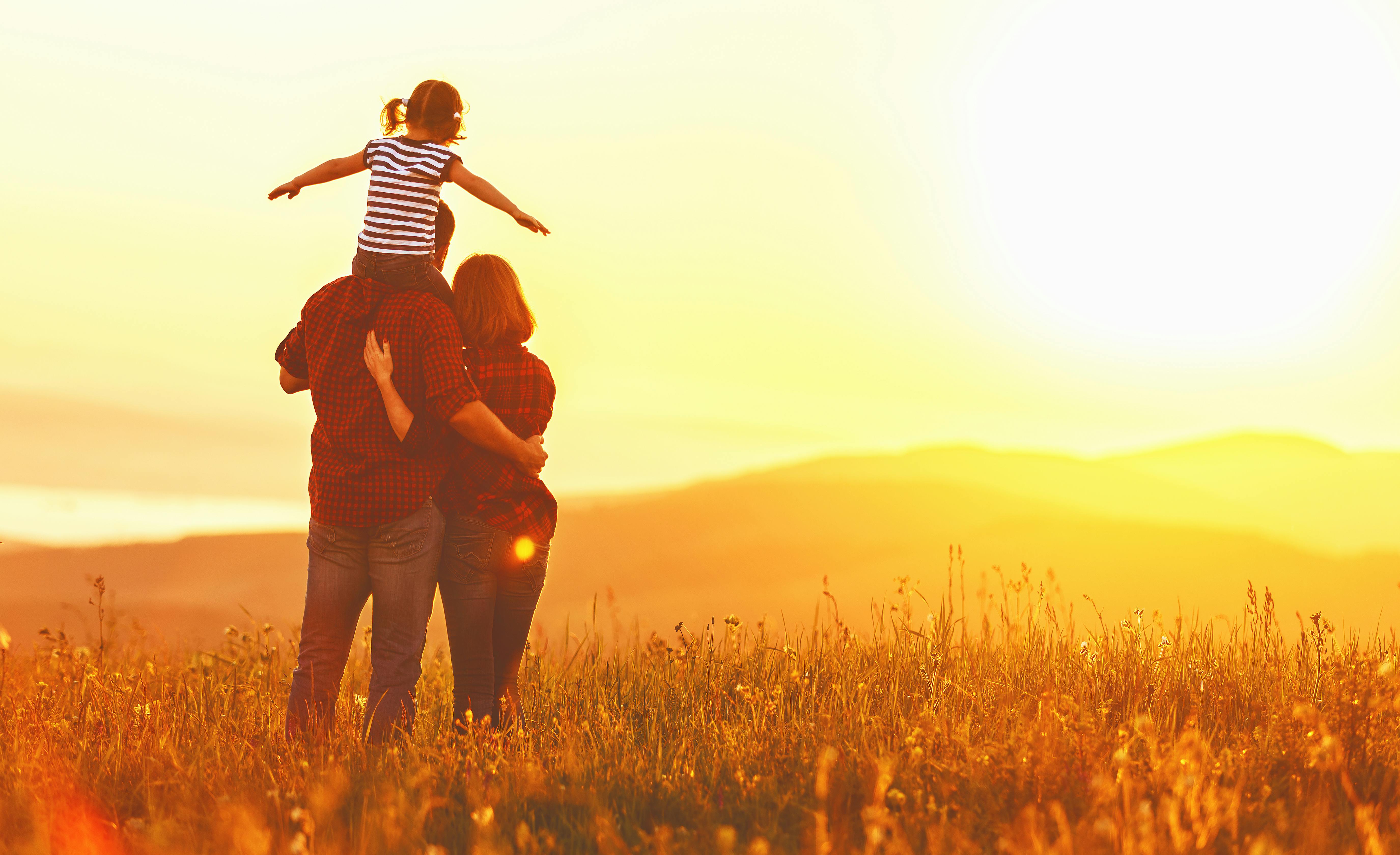 Overvej om børnene skal med på bryllupsrejsen, eller I skal tage et par dage for jer selv. Familie ser solnedgang