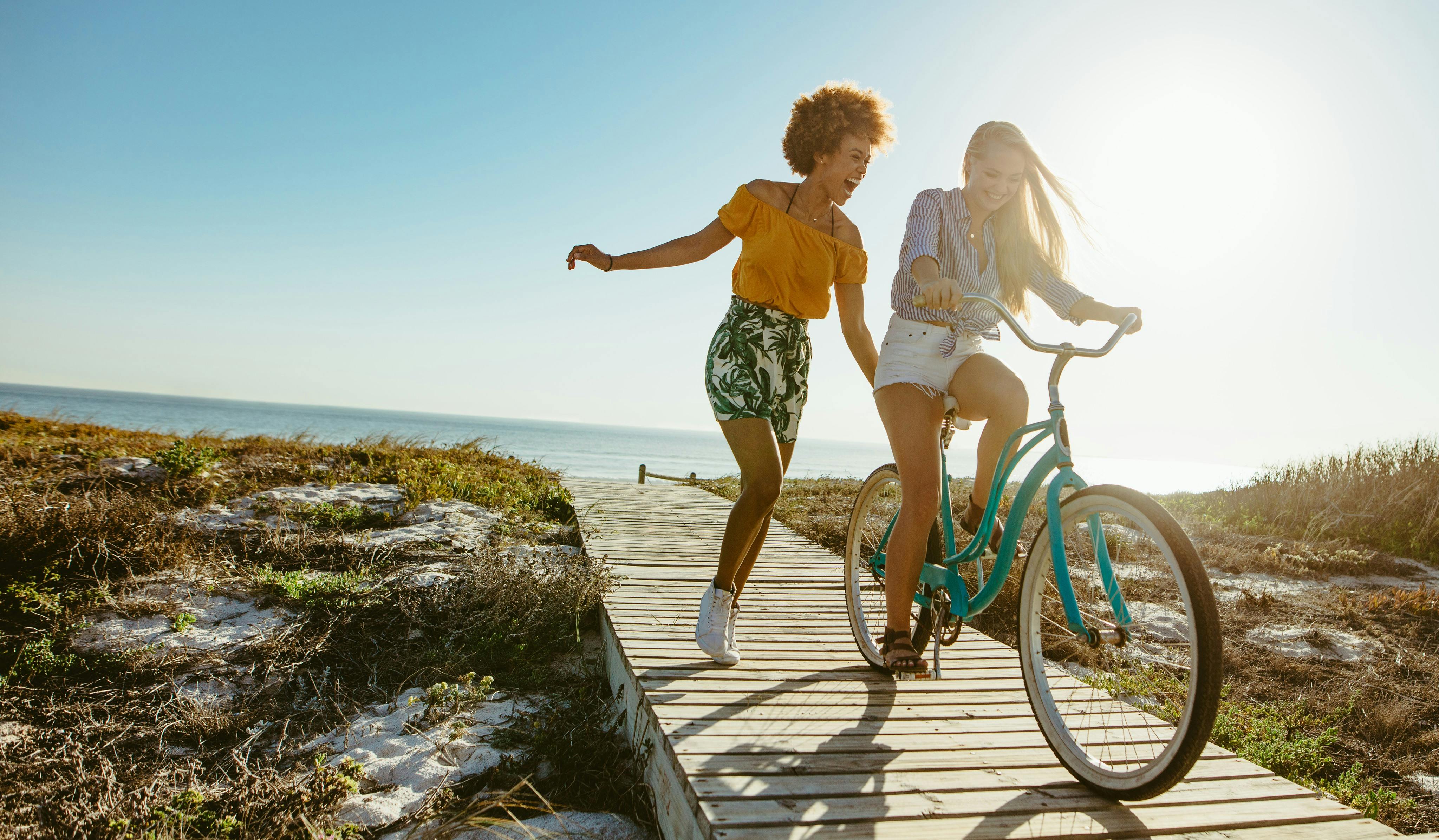 Det er sol og sommer og derfor kan du og dine veninder tage på stranden. Kvinder der hopper og cykler på stranden