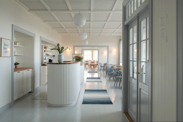De kleuren van de kust komen terug in de aankleding van het restaurant. Svinkløv badehotel restaurant entree met wit hout