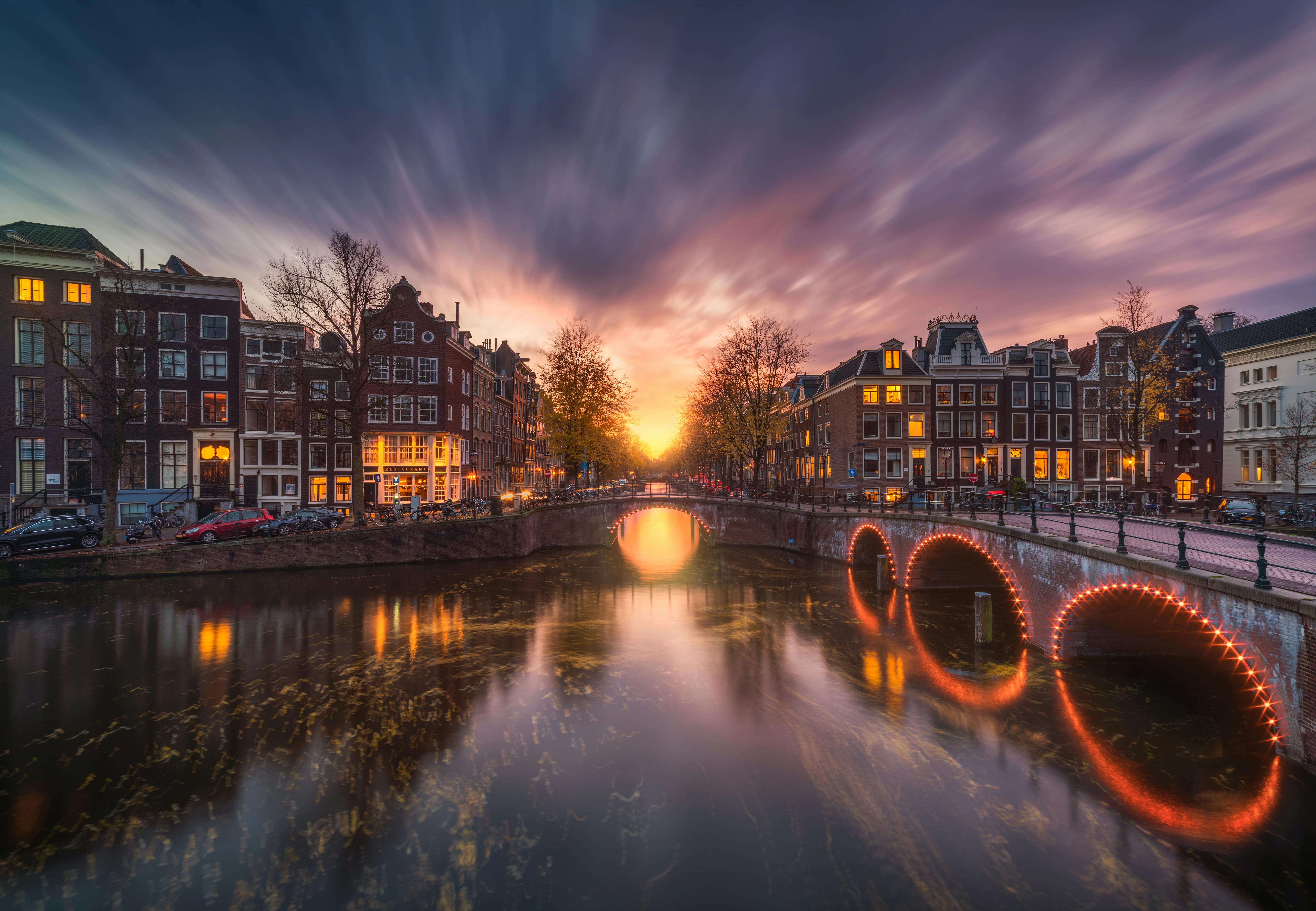 Solnedgang over kanaler i Amsterdam