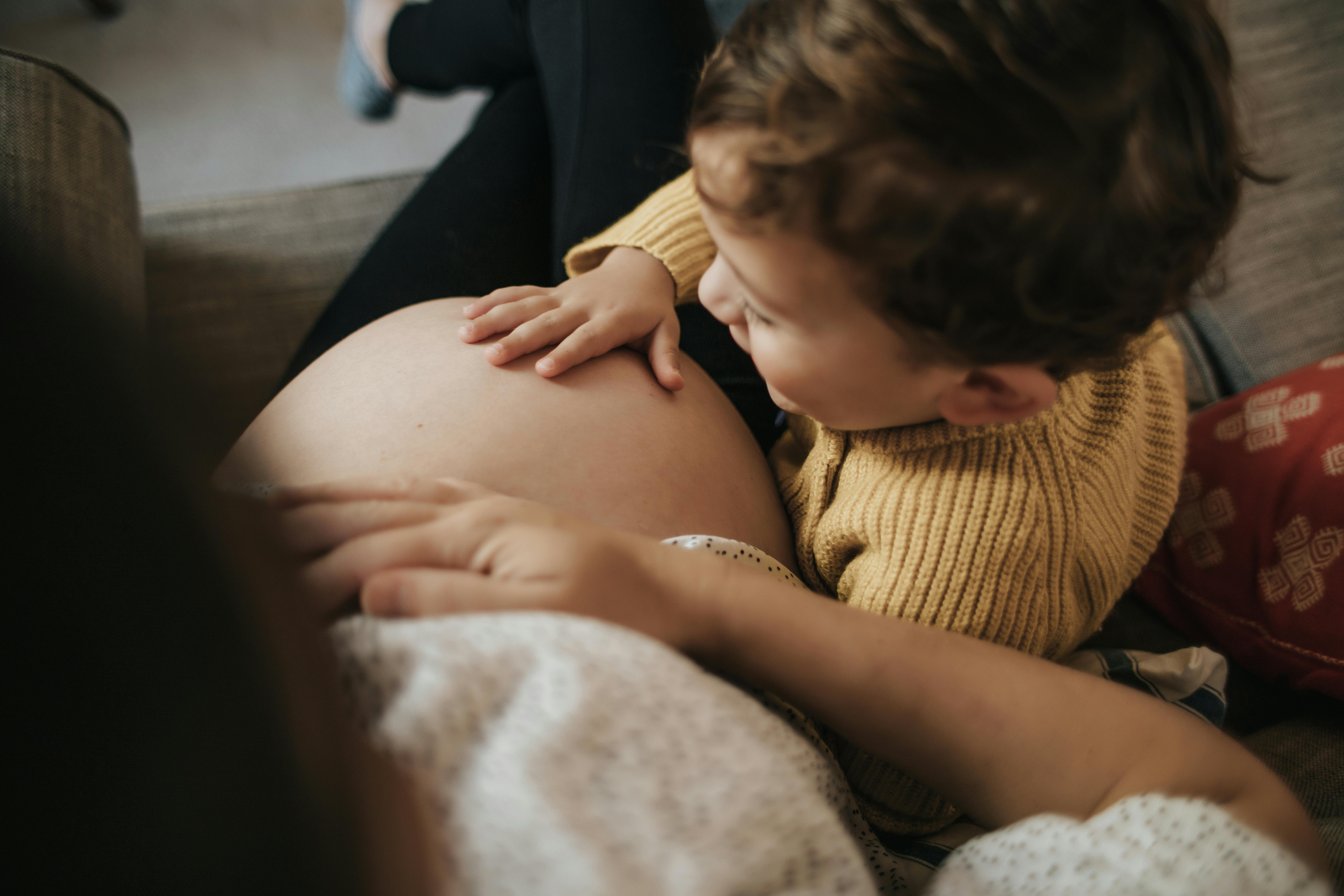 Når du er gravid i uge 36, er fødslen kun få uger væk. Kvinde, som er gravid i uge 36, sidder med sit barn i sofaen