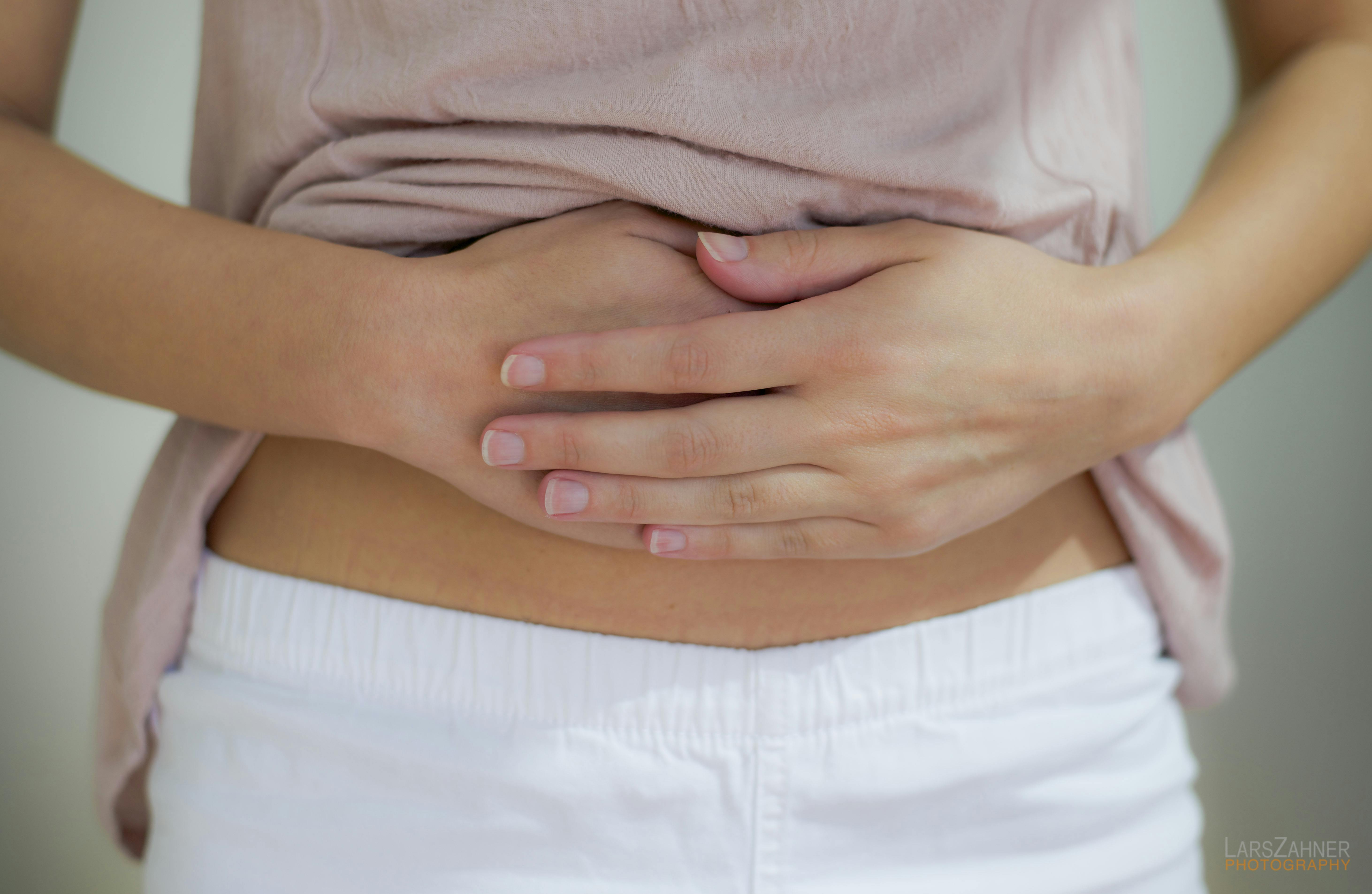 En uregelmæssig menstruation kan for eksempel skyldes hormonforstyrrelser. Kvinde holder sig på maven