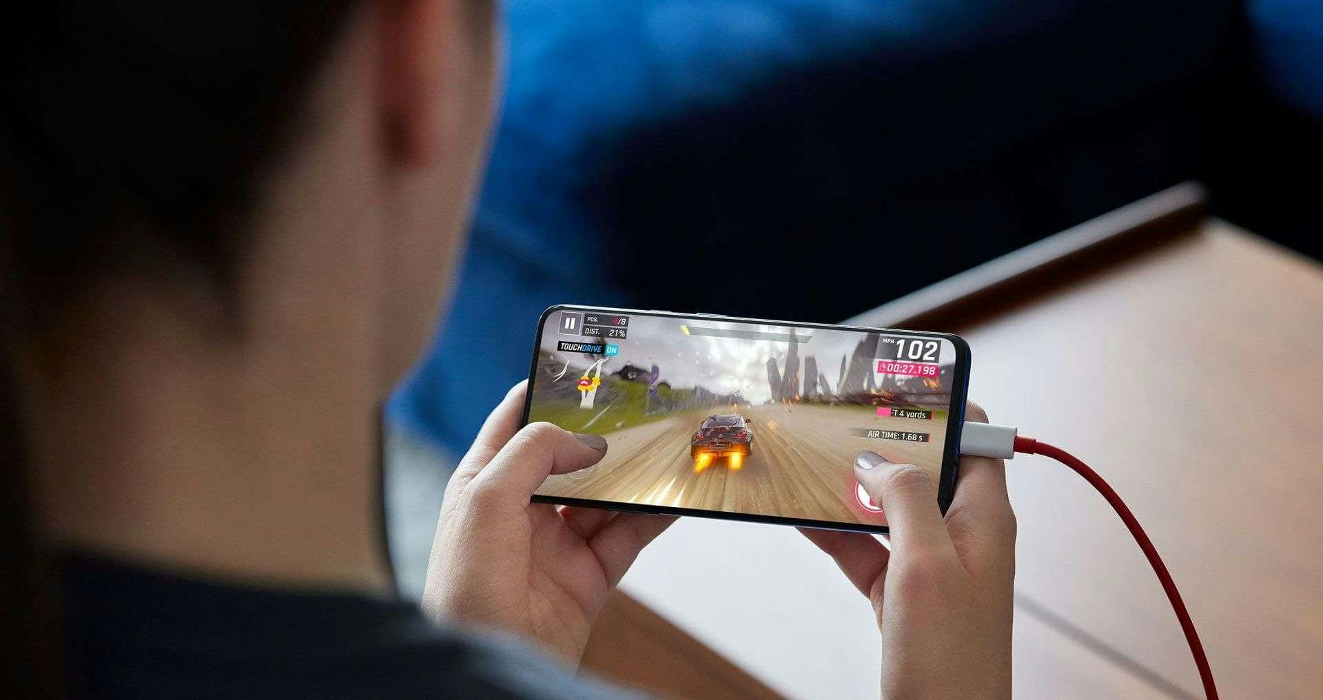OnePlus 7 Pro, joka on latauksessa samalla kun sillä pelataan autopeliä.