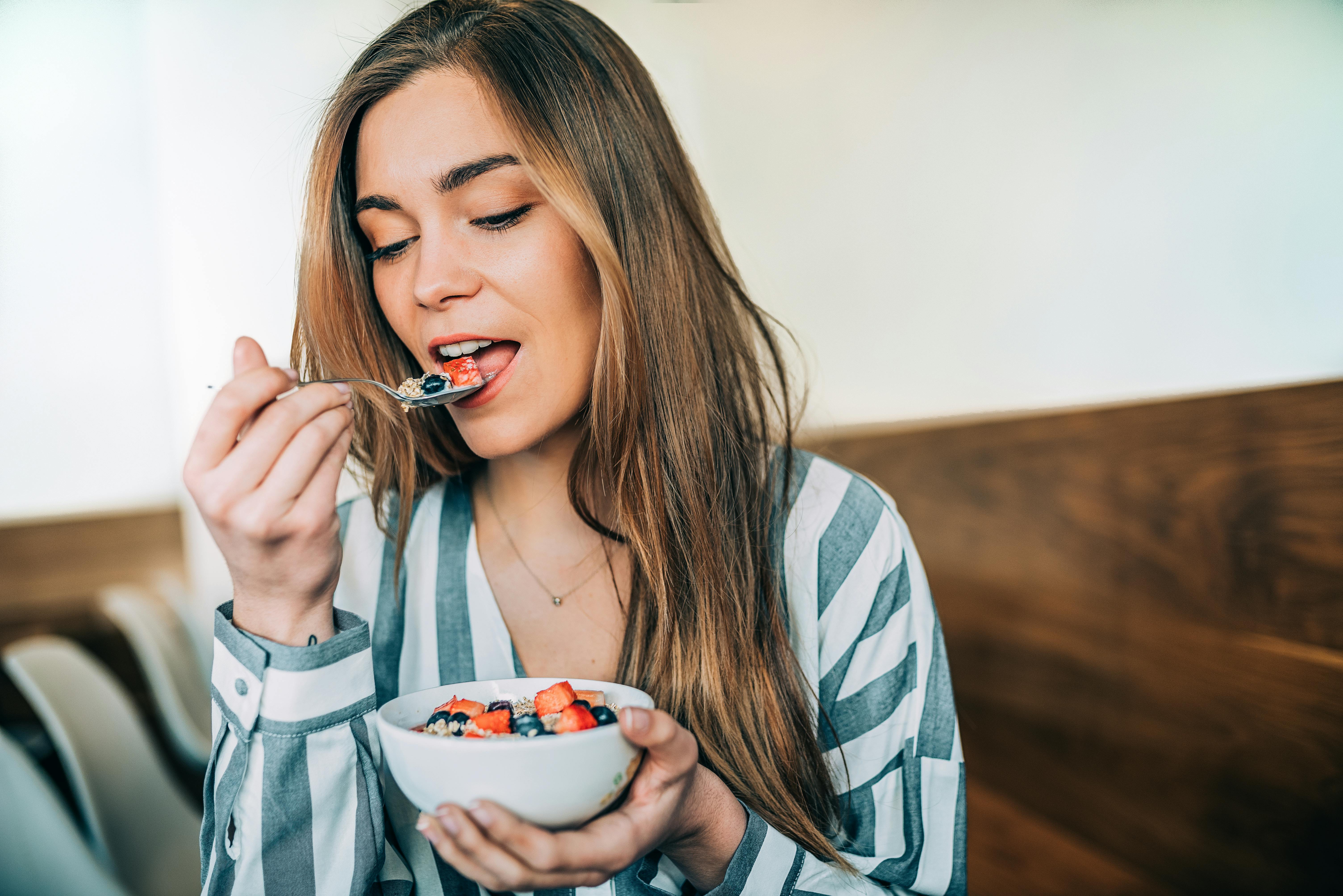 Din tarmflora vil elske yoghurt med frisk frugt. En kvinde spiser youghurt